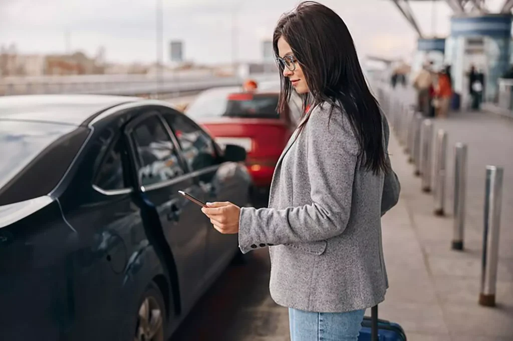 Donna che guarda il suo telefono mentre attende l'arrivo del suo taxi all'aeroporto internazionale di Ginevra