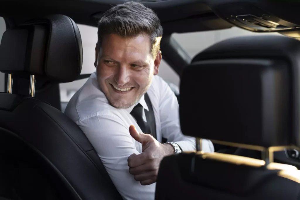 chauffeur de taxi qui sourit à un client sur le trajet aéroport de Genève Gstaad